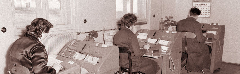 Duas mulheres e um homem a operar máquinas de calcular automáticas em 1960