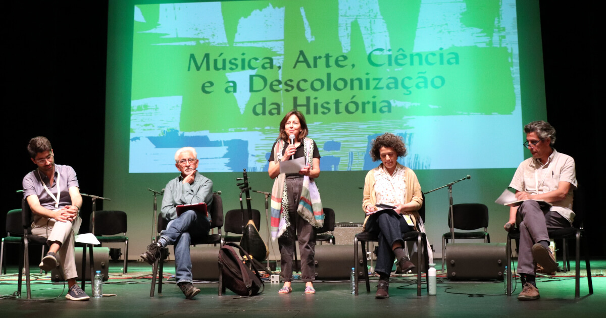 Fotografia do palco do painel "Música, arte, ciência e a descolonização da história”, no Teatro Garcia de Resende, com todos os participantes.