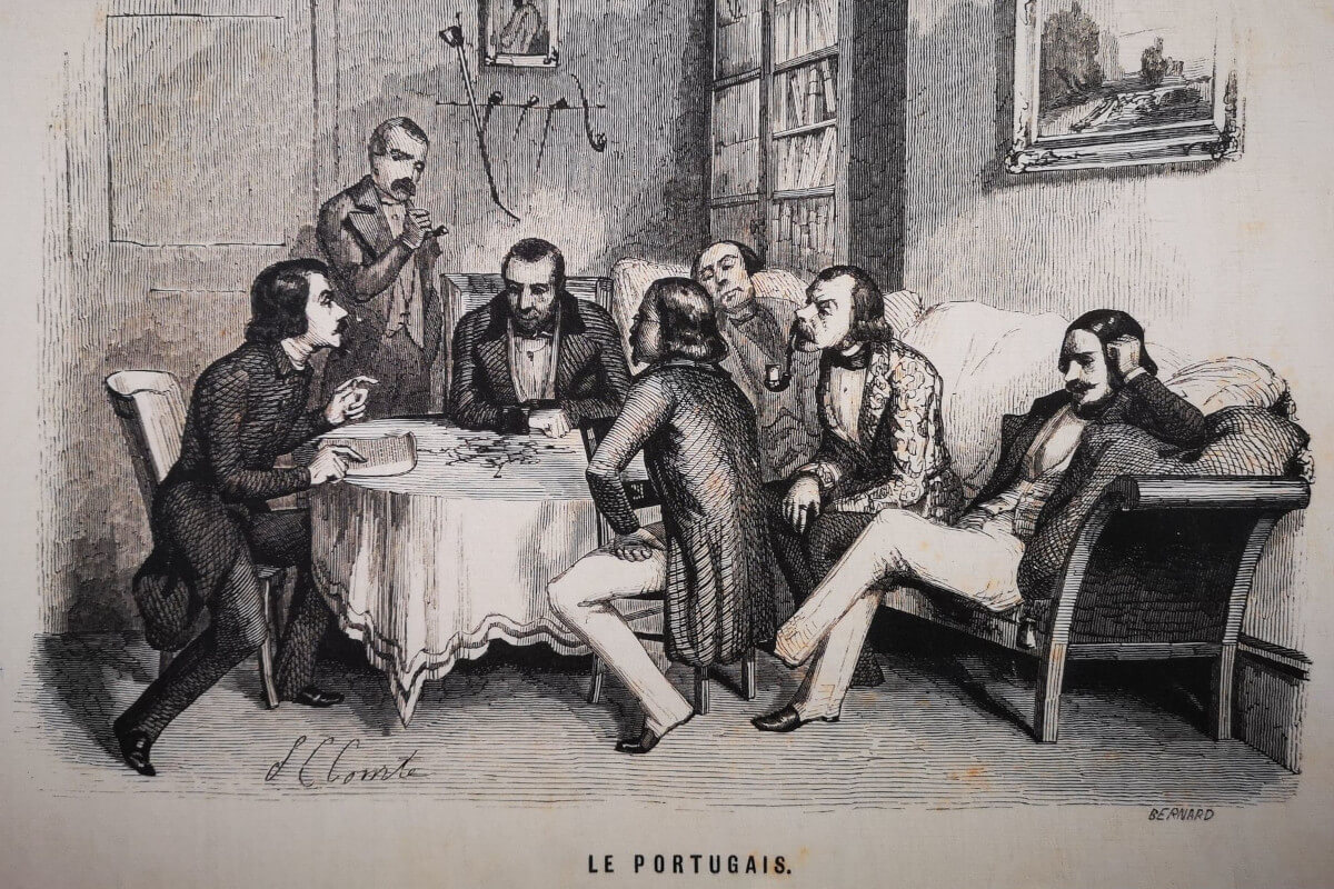 Fotografia da ilustração “Le Portugais. Les étrangers à Paris.”, de 1844, que mostra vários homens bem-vestidos, alguns a fumar cachimbo, sentados em volta de uma mesa e num sofá junto à mesma.