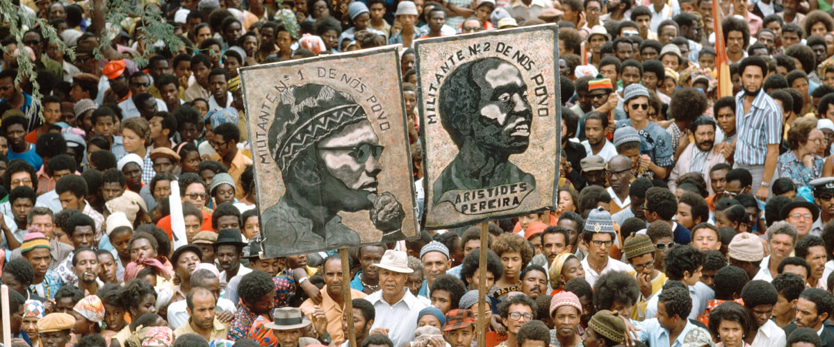 Imagem ilustrativa da apresentação do livro “The Liberation of Portuguese Africa, 1961-1975. International Exile and Solidarity”. Fotografia de uma multidão, onde se destacam dois cartazes, um de Amílcar Cabral e outro de Aristides Pereira, captada durante a missão da ONU às ilhas de Cabo Verde em 1975.
